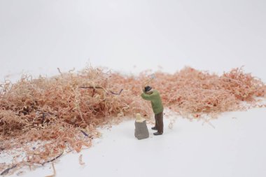 Eltestereli küçük insanlar kalemi kesiyor.