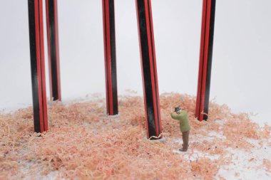 Eltestereli küçük insanlar kalemi kesiyor.