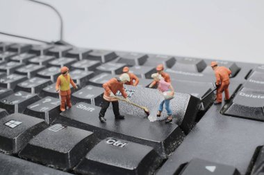 Minyatür insanlar beyaz klavye bilgisayarını temizliyor..