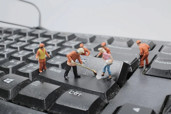 the Miniature people cleaning white keyboard computer.