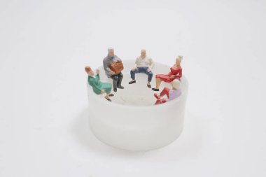 Mini figür beyaz arka planda oturuyor.