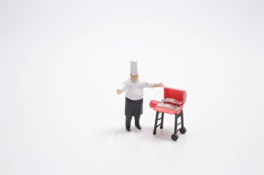 The mini Chef prepares meat on the barbecue.