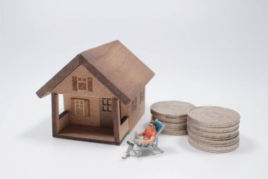 Minyatür evin önünde bir yığın madeni parası olan insanlar..