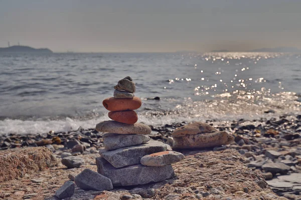 Balanced stones on a pebble beach during sunset.