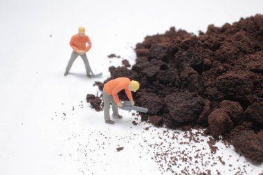 Küçük işçi figürleri öğütülmüş kahve üzerinde çalışıyor