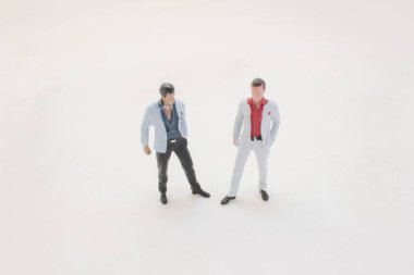 miniature men in stylish suits stand apart on a clean white surface,