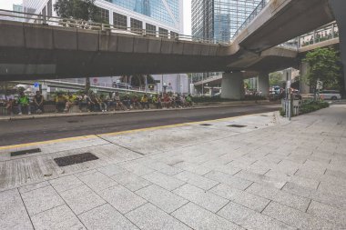 Yoğun bir şehir manzarası, bir kaldırım kenarında oturan uzun bir insan kuyruğunu gösteriyor.