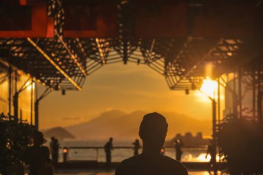 Siluetli ziyaretçiler sıcak bir günbatımı gibi dekoratif cam bir çatı altında duruyorlar.