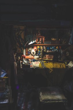 İplik makaralarıyla dolu, küçük, loş bir dikiş alanı