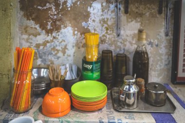 Tek kullanımlık bardaklarla dolu küçük bir servis arabası, istiflenmiş tabaklar.