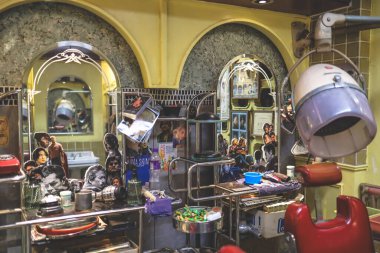 Aynalar, eski sandalyeler ve çeşitli aletlerle dolu eski bir berber sahnesi.