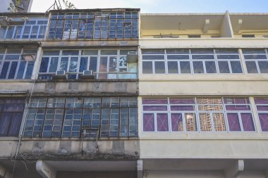 Dense urban building facade with stacked glass windows and weathered concrete