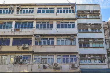 Dense urban building facade with stacked glass windows and weathered concrete