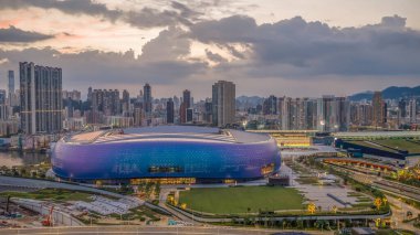 Modern stadyum Alacakaranlık Kowloon siluetinin altında aydınlandı