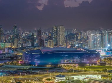 Modern stadyum Alacakaranlık Kowloon siluetinin altında aydınlandı