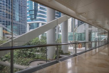 Çağdaş bir ofis binasının içinde camdan duvarlar olan kapalı bir koridor.