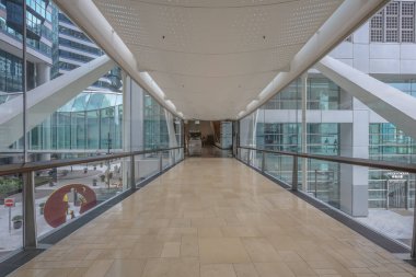 Çağdaş bir ofis binasının içinde camdan duvarlar olan kapalı bir koridor.