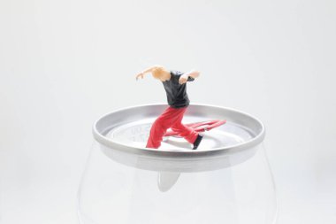 Tuhaf minyatür figürler metal bir teneke üzerinde dengede duruyorlar.