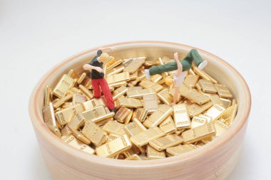 Altın külçeleri arasında gezinen küçük heykelciklerin tuhaf manzarası.