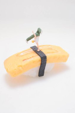 Oyuncu minyatür figür tamago nigiri diliminin üzerinde duruyor.,