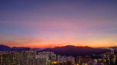 Yoğun bir şehir olarak dramatik bir günbatımı, gökyüzünü turuncu tonlarda boyar.