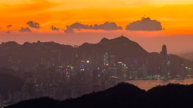 Yoğun bir şehir olarak dramatik bir günbatımı, gökyüzünü turuncu tonlarda boyar.
