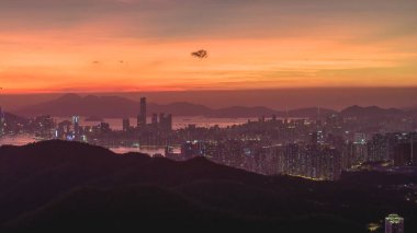 Yoğun bir şehir olarak dramatik bir günbatımı, gökyüzünü turuncu tonlarda boyar.