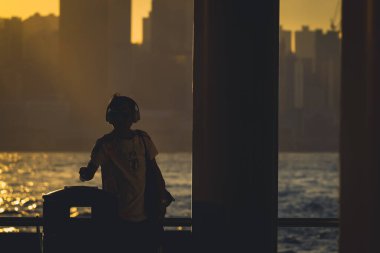 Siluetli figürler gün batımında tırabzanın kenarında duruyor, parıldayan bir şeye bakıyor, 16 Kasım 2025