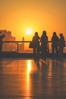 Rakamlar cam korkulukların yanında parlak turuncu bir gün batımı gibi duruyor, 16 Kasım 2025 