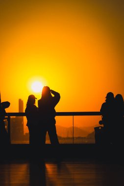 Rakamlar cam korkulukların yanında parlak turuncu bir gün batımı gibi duruyor, 16 Kasım 2025 