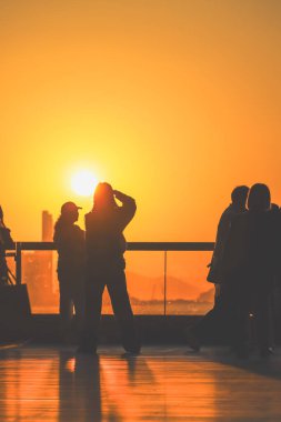 Rakamlar cam korkulukların yanında parlak turuncu bir gün batımı gibi duruyor, 16 Kasım 2025 