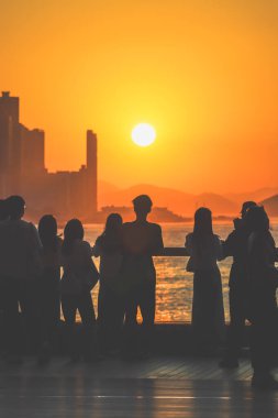 Siluetli grup güneşli bir balkonda duruyor şehrin ufuk çizgisi parlarken 16 Kasım 2025 