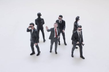 Siyah takım elbiseli ve güneş gözlüklü adamlar güvenlik oluşturur.