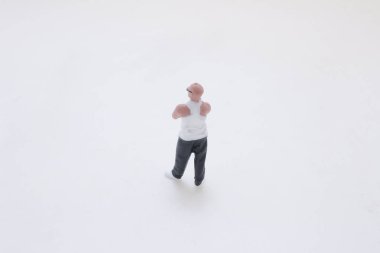 Küçük bir erkek heykeli beyaz bir yüzey üzerinde duruyor.