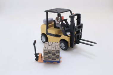 Oyuncak forkliftle şoför, kutulu bir paleti minyatür bir W ile hareket ettirir.