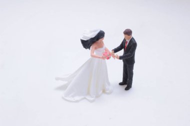 Minyatür düğün sahnesinde beyaz bir gelinlik ve buketli bir gelin görülüyor.