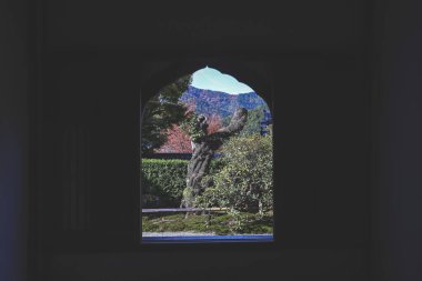 Huysuz bir iç mekan, açık hava manzarasını çerçeveler. Bir kemer penceresi, 23 Kasım 2025