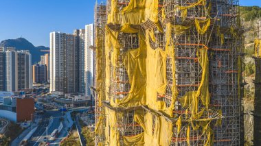 11 Ocak 2026 'da sarı brandaların dalgalandığı yüksek katlı bir cepheyi kapsıyor.