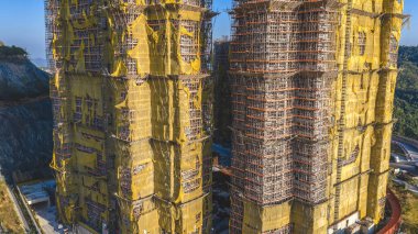 11 Ocak 2026 'da sarı brandaların dalgalandığı yüksek katlı bir cepheyi kapsıyor.