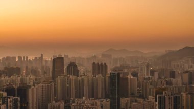 Yumuşak, parlak günbatımı renkleri Kowloon binalarını ve 11 Ocak 2026 'yı aydınlatır.