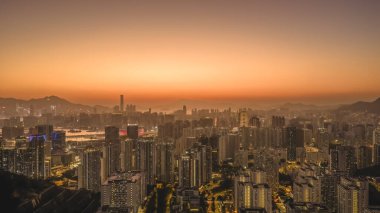 Yumuşak, parlak günbatımı renkleri Kowloon binalarını ve 11 Ocak 2026 'yı aydınlatır.