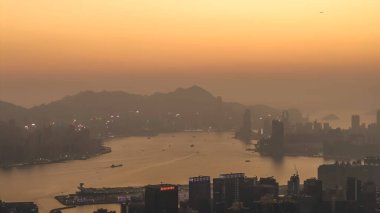 18 Ocak 2026 'da sisli Hong Kong ufuk çizgisinde ılık, parlayan güneş batıyor.