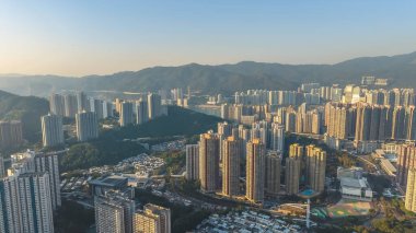 Temiz güneş ışığı Tsing Yi binaları, tepeler ve kıyı şeridi 10 Ocak 2026 'yı vurguluyor