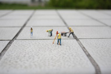 Küçük model işçiler dokulu fayanslar üzerinde koordineli görevler yaparlar.