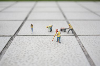 Küçük model işçiler dokulu fayanslar üzerinde koordineli görevler yaparlar.