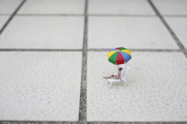 Minik model, çok renkli güneş kreminin altında rahatça dinleniyor.