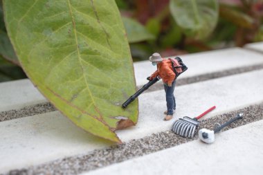 Küçük model, yemyeşil yapraklarla çevrili bahçe işlerini yapıyor.