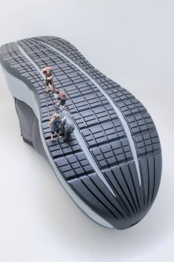 Küçük taşra figürleri su bufalolarını büyük beden spor ayakkabıları arasından geçirir.