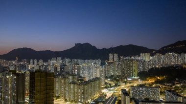 Aydınlatılmış konut kuleleri 15 Şubat 2026 'da hareketli akşam bölgesinin üzerinde yükseliyor.