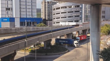 Elektrik banliyö treni, binaların yanındaki yüksek raylar boyunca hareket ediyor, 16 Şubat 2026